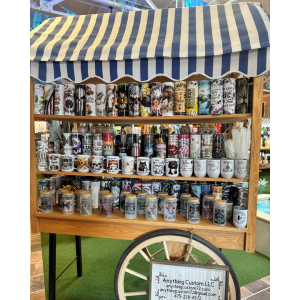 A cart with a blue striped roof and 3 shelves full of cups and drinkware