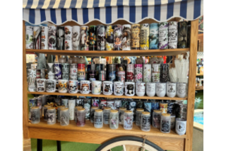 A cart with a blue striped roof and 3 shelves full of cups and drinkware