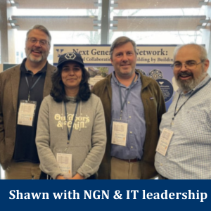 Shawn with three other NGN team members in front of an NGN poster